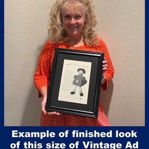 May include: Framed vintage advertisement with a black frame. The ad features a cartoon character holding a telephone, with the text "Helps put more smiles in the day!" at the top. The bottom of the frame has the text "Example of finished look of this size of Vintage Ad".