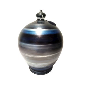 Pode incluir: Um cofrinho de cerâmica com um design listrado em preto, azul e cinza. O cofrinho tem uma pequena tampa preta com um cordão.