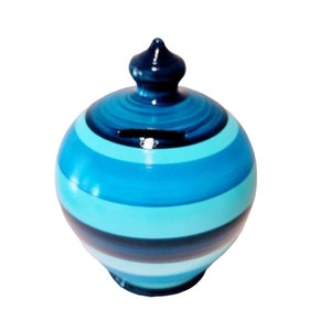 May include: Blue and turquoise striped ceramic piggy bank with a dark blue lid.