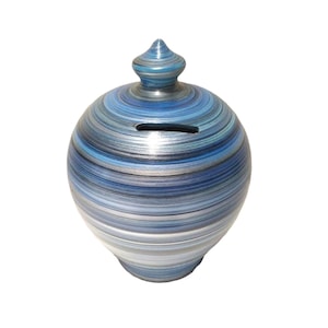 May include: A blue and silver striped ceramic money box with a rounded shape and a small, pointed lid.
