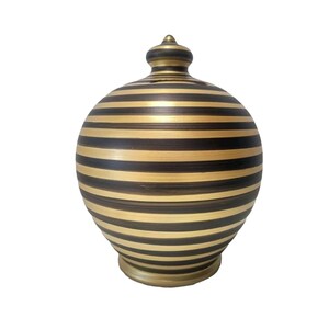 May include: A black and gold striped ceramic piggy bank with a round body and a small lid.