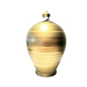 May include: A gold ceramic piggy bank with a swirl design. The piggy bank has a small opening on the top for coins.
