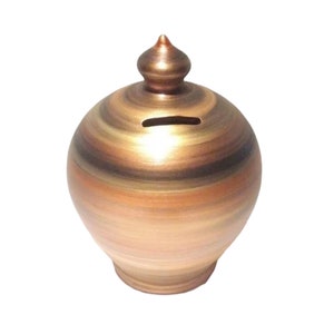 Könnte beinhalten: Ein handgefertigtes, rundes Sparschwein mit metallischer Bronzefinish. Die Bank hat einen Schlitz zum Einwerfen von Münzen und eine dekorative, spitze Oberseite. Das Äußere zeigt horizontale Bänder in Braun-, Gold- und Bronzetönen.