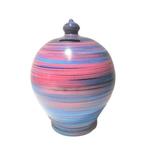 May include: A ceramic money box with a swirl design in shades of pink, blue and black.