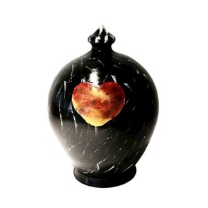 Pode incluir: Cofrinho de cerâmica preto com um coração vermelho e dourado pintado na frente.