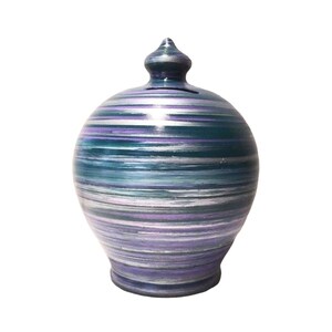 Puede incluir: Una alcancía de cerámica con un diseño de espiral en tonos de verde azulado, morado, plateado y blanco.