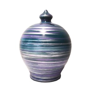 May include: A ceramic money box with a swirl design in shades of teal, purple, and silver.
