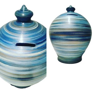 Pode incluir: Um cofrinho de cerâmica azul e branco com um padrão de espiral. O cofrinho tem uma fenda lateral para moedas.