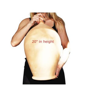 May include: A large, terracotta-coloured clay pot, 20 inches in height. The pot is being held by a person, but the person's hands are not visible in the image.