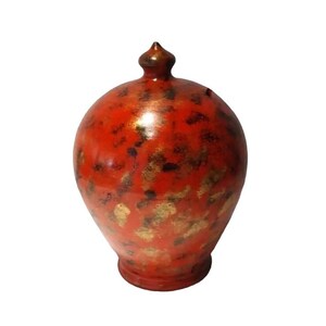 May include: A red ceramic piggy bank with gold accents. The piggy bank has a rounded shape with a pointed top.