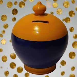 May include: A round, two-toned piggy bank with a slot for coins. The top half is painted yellow-orange, and the bottom half is dark blue. A small, decorative knob sits on top. Gold coins float in the background.