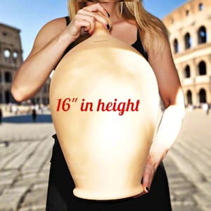 Può includere: Un grande vaso di ceramica beige, alto circa 41 cm, è tenuto davanti a uno sfondo sfocato. Il vaso ha un corpo arrotondato e un collo stretto. Il testo "16" in height" è stampato in rosso sul vaso.