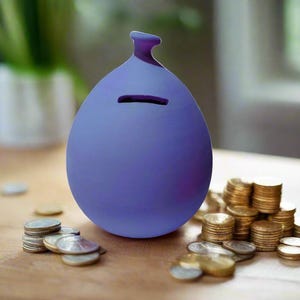 May include: A purple ceramic money box shaped like a balloon with a slot for coins. The money box is surrounded by stacks of gold coins.