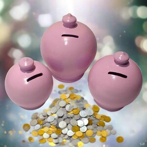 May include: Three pink ceramic piggy banks with coin slots and small, rounded tops. A pile of gold and silver coins sits below the banks. The banks are spherical and have a smooth, glossy finish.