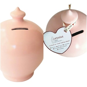May include: A pink ceramic piggy bank with a heart-shaped tag that reads "CATERINA Handmade with all my heart... as much as I loved making them!"