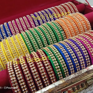 May include: A set of colorful silk bangles with rhinestone embellishments. The bangles are arranged in a wooden box with a lock and key.
