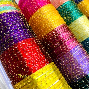 May include: A selection of vibrant bangles in a variety of colours, including purple, red, yellow, pink, green, and blue. Each bangle is decorated with tiny, gold-coloured details. The text "The Silk Box Art" is visible.