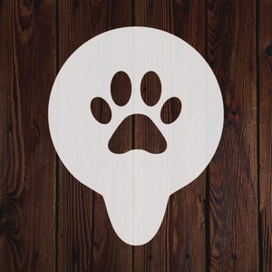 Può includere: Stencil a forma di impronta di zampa bianca su uno sfondo di legno marrone.