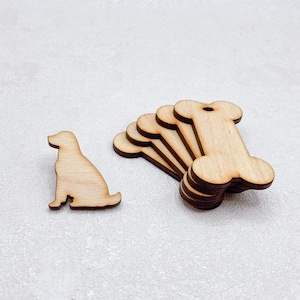 Peut inclure: Découpes en bois sur le thème des chiens. L'une est une silhouette de chien, les autres ont la forme d'os. Les découpes sont en bois clair, adaptées aux travaux manuels ou aux décorations. Les os ont un petit trou.