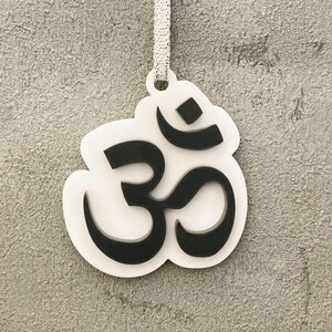 May include: White ornament with a black Om symbol. The ornament has a hole at the top for hanging.
