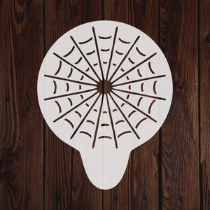 May include: White plastic stencil shaped like a spider web. The stencil has a circular design with radiating lines and curved edges.