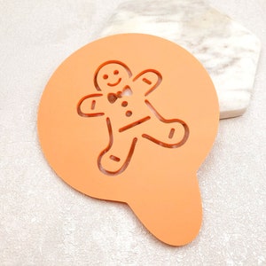 May include: Orange plastic gingerbread man stencil for decorating cakes, cookies, or other baked goods.