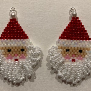 May include: A pair of beaded Santa Claus earrings with white beards and red hats.