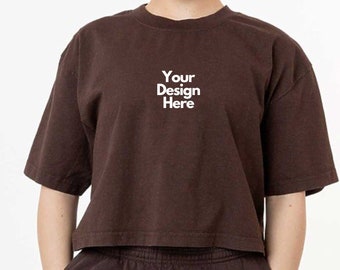 May include: A dark brown cropped t-shirt with short sleeves and a crew neckline. The center of the chest features the white text "Your Design Here". The shirt is paired with matching dark brown sweatpants with an elastic waistband.