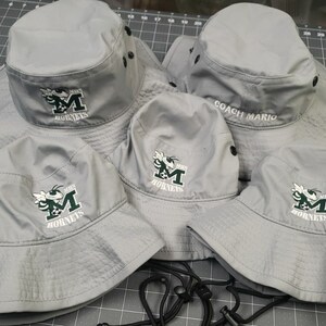 May include: Five gray bucket hats with black trim and a green and white embroidered hornet logo. One hat has the text "Coach Mario" embroidered on the front.