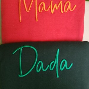 May include: Two sweatshirts, one red with the word "Mama" embroidered in orange, and one black with the word "Dada" embroidered in green.