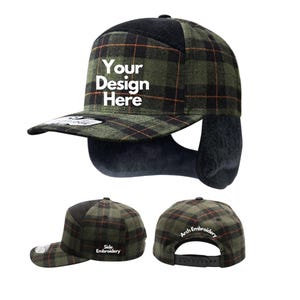 May include: A green and black plaid cap with ear flaps. The cap has a flat brim and a black top. The text "Your Design Here" is on the front. The side says "Side Embroidery" and the back says "Arch Embroidery".