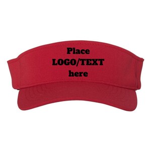 May include: A solid red sun visor featuring the black text "Place LOGO/TEXT here" centered on the front panel. The visor has a curved brim with visible stitching detail and a structured crown design, providing a clear view of the front surface.
