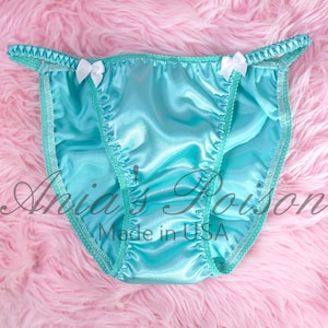 May include: A turquoise blue satin lingerie with white satin bows on the sides. The lingerie has a delicate lace trim and is made in the USA.