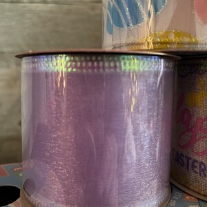 K&ouml;nnte beinhalten: Eine Rolle schimmerndes violettes Band mit wei&szlig;em gepunktetem Rand. Das Band ist um einen Pappzylinder gewickelt.