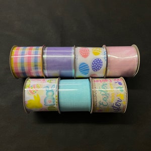 K&ouml;nnte beinhalten: Sechs Rollen Osterband. Die B&auml;nder haben verschiedene Muster, darunter Karos, Punkte und Hasen. Die B&auml;nder sind alle in Pastellfarben, darunter Rosa, Blau, Gelb und Lila.