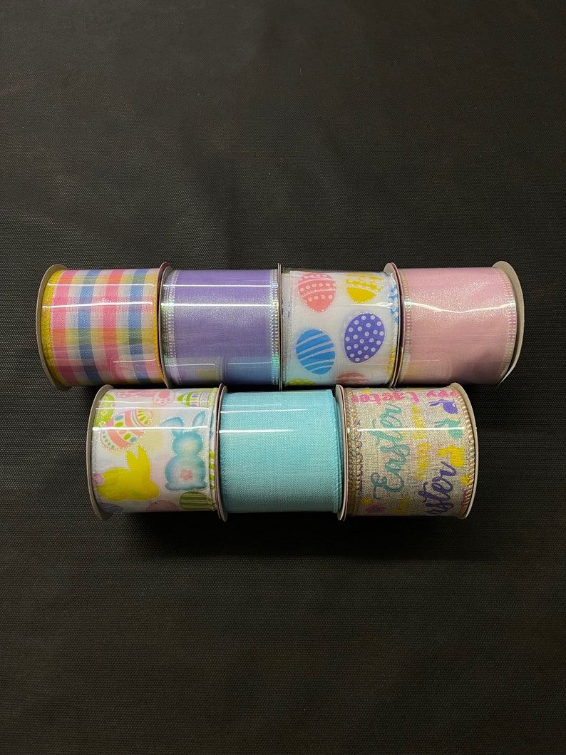 K&ouml;nnte beinhalten: Sechs Rollen Osterband. Die B&auml;nder haben verschiedene Muster, darunter Karos, Punkte und Hasen. Die B&auml;nder sind alle in Pastellfarben, darunter Rosa, Blau, Gelb und Lila.