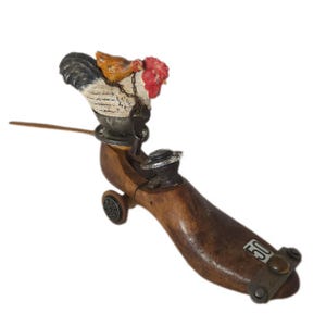 May include: A vintage wooden shoe form with a decorative rooster and hen figurine. The rooster has a red comb and a black and white body. The shoe form has a metal wheel and a metal plate with the number 50.