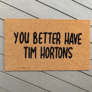 May include: A brown coir doormat with the text "You better have Tim Hortons" in black lettering.