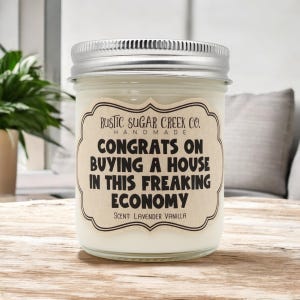 Könnte beinhalten: Eine Glas-Kerze in einem Einmachglas mit einem braunen Etikett, auf dem steht "RUSTIC SUGAR CREEK CO. HANDMADE CONGRATS ON BUYING A HOUSE IN THIS FREAKING ECONOMY SCENT: LAVENDER VANILLA"