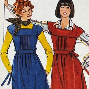 May include: Two women wearing dresses with contrasting colors. The woman on the left is wearing a blue dress with a yellow shirt and a red and black scarf. The woman on the right is wearing a red dress with a white and blue striped shirt.
