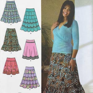 May include: A sewing pattern illustration featuring six variations of skirts, including tiered, ruffled, and A-line designs in various colors and patterns, alongside a photograph of a light blue wrap top paired with a brown floral print skirt.