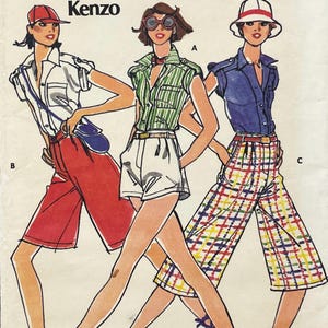 May include: A vintage Kenzo sewing pattern illustration featuring three outfits. Outfit B shows a white shirt, red shorts, and a red cap. Outfit A displays a green striped shirt and white shorts. Outfit C features a blue shirt and plaid culottes.