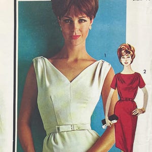 May include: A sewing pattern envelope featuring two dress designs. One is a sleeveless, light-coloured dress with a V-neckline and a thin waist belt. The second is a red dress with short sleeves, a round neckline, and a matching belt at the waist.