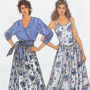 Op de afbeelding: Een naaipatroonillustratie met twee outfits. De ene is een blauwe overslagtop met lange mouwen en een bijpassende ceintuur over een rok met bloemenprint. De andere is een mouwloze jurk met ronde hals, witte basis en blauw met paars bloemmotief.