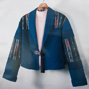 May include: A blue jacket with a textured finish, featuring long sleeves with patterned panels, a wide collar, and a single black toggle closure with a hanging tassel. The jacket is layered over a light pink mock neck top on a hanger.