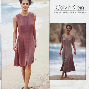 May include: A sewing pattern envelope for Calvin Klein Vogue American Designer dresses. View A is a sleeveless, knee-length button-front dress. View B is a short-sleeved, ankle-length button-front dress. Both designs feature a simple, fitted bodice.