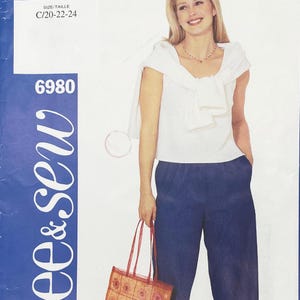 Puede incluir: Un sobre de patrón de costura etiquetado 6980 y See & Sew, que muestra una blusa blanca sin mangas con un suéter drapeado sobre los hombros y pantalones azul oscuro. El rango de tallas C/20-22-24 está impreso en la parte superior.