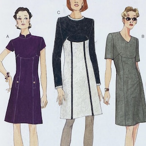 May include: Three dresses are displayed. The first is a dark purple, short-sleeved dress with a mandarin collar and two front pockets. The second is a gray, short-sleeved dress with a V-neck. The third dress is black and white with long sleeves.