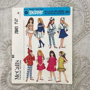 May include: A McCall's printed pattern envelope for a 9-inch Skipper doll, featuring illustrations of eight different outfits labelled A through H. The blue and white packaging displays various clothing styles including dresses, sweaters, and trousers.