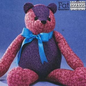 May include: A handmade teddy bear with a blue ribbon. The bear's head and arms are a patterned red fabric, while the body is a patterned purple fabric. The bear has black button eyes and the text "Fat Quarters" is visible.